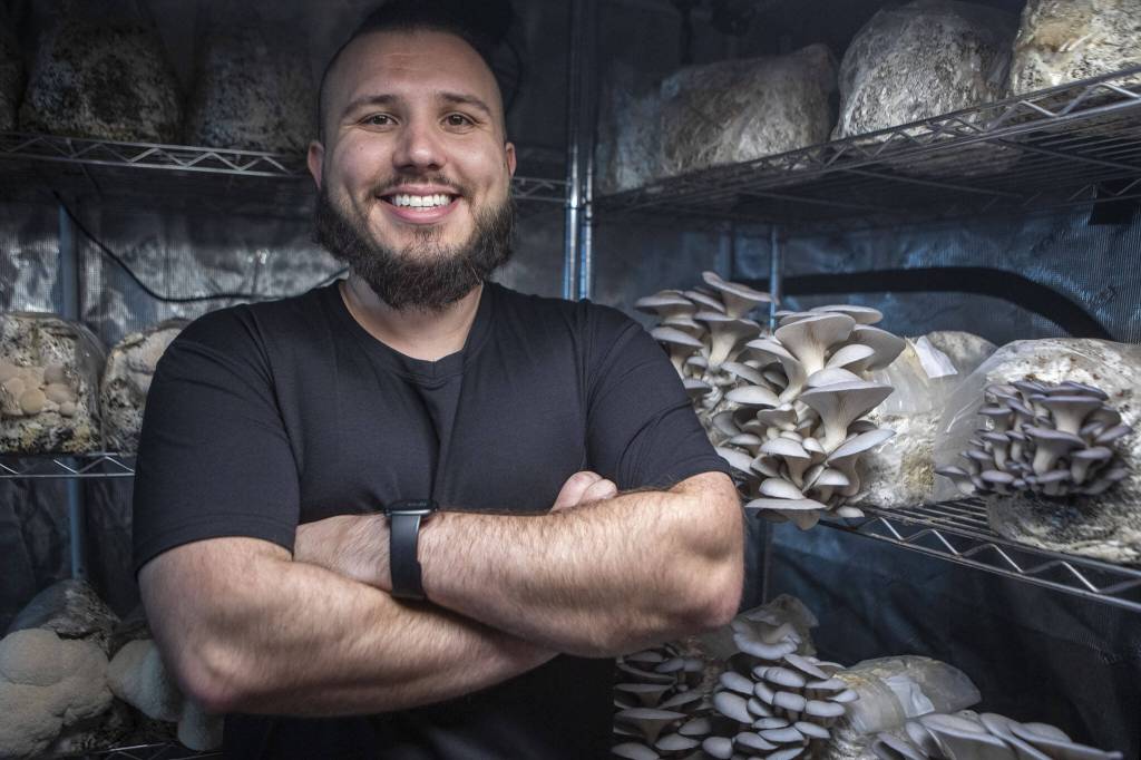 Nathanael Engen poses for a photo with mushrooms he grows at his property in Everett, Washington on Monday, March 27, 2023. Engen summarizes his business as cultivating mushrooms, and healthy communities. (Annie Barker / The Herald)