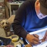Brian Bassets dog Astro looks up at him while Basset works in his studio on Wednesday, June 7, 2023, in Edmonds, Washington. (Olivia Vanni / The Herald)