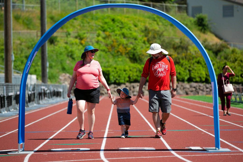 Dani and Ryan Driscoll finish the first of four laps with their son Willy, 2, during the Robert C. Polk Heart Healthy Education Event on Saturday, June 3, 2023, at Memorial Stadium in Everett, Washington. The Driscolls said they came out to the event to support Tara Polk and to honor the memory of her husband, Robert. (Ryan Berry / The Herald)