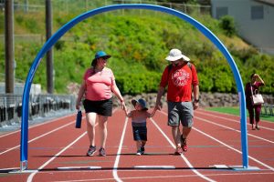Dani and Ryan Driscoll finish the first of four laps with their son Willy, 2, during the Robert C. Polk Heart Healthy Education Event on Saturday, June 3, 2023, at Memorial Stadium in Everett, Washington. The Driscolls said they came out to the event to support Tara Polk and to honor the memory of her husband, Robert. (Ryan Berry / The Herald)