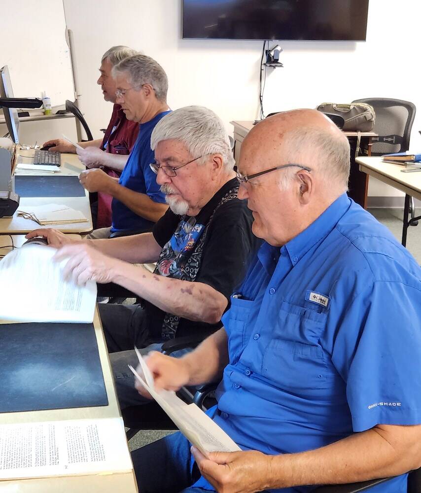 From left to right, volunteers Tom Thorleifson, Sam Crager, Fred Cruger and Jim Liming leaf through historic documents at the Darrington Ranger Station on May 20, 2023, in Darrington, Washington. (Adam Sowards / For The Herald)