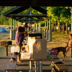 Charles Robbins pieces together a steak dinner for his family as young Athea Miller plays with the family dog, Lana, under one of the shelters at Kayak Point on Monday, June 12, 2023, in Stanwood, Washington. (Ryan Berry / The Herald)