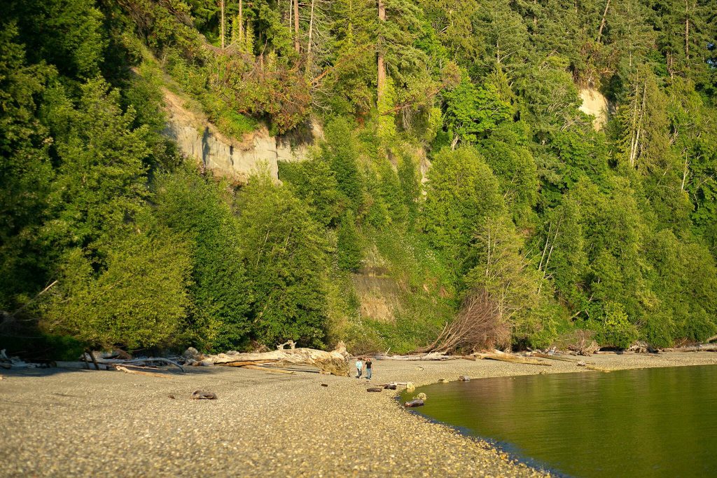A couple walks back towards the park along the south shoreline of Kayak Point on Monday, June 12, 2023, in Stanwood, Washington. (Ryan Berry / The Herald)