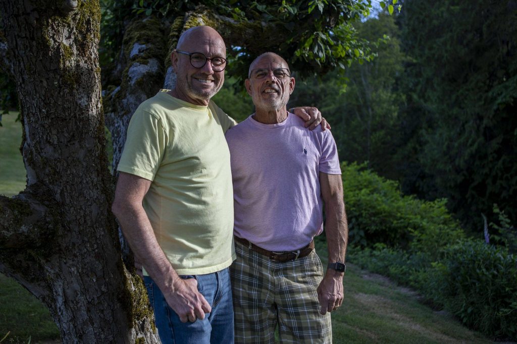 Doug Blay, left, and Tim Pfahl, right, pose for a photo at their home in Everett. Theyve had nine Pride flags stolen from their yard over two years. (Annie Barker / The Herald)