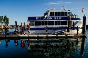 Islanders disembark the Hat Island Ferry, which is called the “Hat Express,” in 2018. At the top of the ramp stands Ray Brown, the captain. Below him on the dock are crew members Ryan Taisey, first mate (left) and Michael Jablinske. (Dan Bates / The Herald)