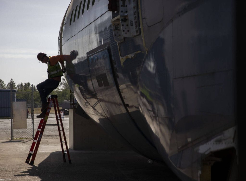 A man climbs out of the fuselage after it is placed on Thursday, June 15, 2023 in Everett, Washington. (Olivia Vanni / The Herald)