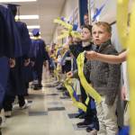 Trenton Sankey, 6, looks up at Everett High School graduates as they walk down the hall of Whittier Elementary School on Friday, June 16, 2023 in Everett, Washington. (Olivia Vanni / The Herald)