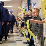 Trenton Sankey, 6, looks up at Everett High School graduates as they walk down the hall of Whittier Elementary School on Friday, June 16, 2023 in Everett, Washington. (Olivia Vanni / The Herald)