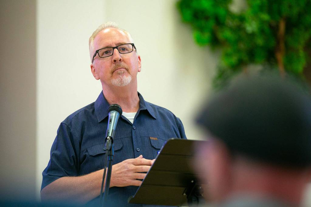 Dennis Kelly, founder and president of homeless outreach group MercyWatch, listens as members of the audience shout questions and complaints during a public meeting regarding a proposed homeless day shelter at Our Lady of Hopes parish hall Thursday, June 29, 2023, in Everett, Washington. (Ryan Berry / The Herald)