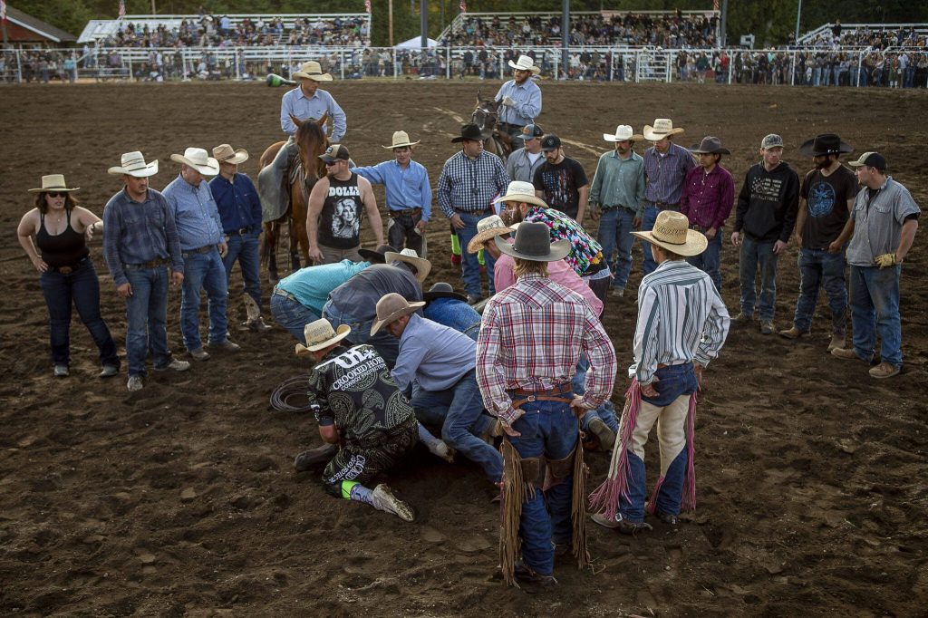 Managers and participants gather to asses a hurt horse during the Timberbowl Rodeo in Darrington, Washington on Saturday, June 24, 2023. (Annie Barker / The Herald)