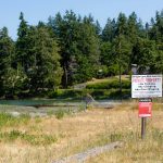 The southern side of the Harrington Lagoon neighborhood is seen beyond a Harrington Lagoon Water Association sign on June 22, 2023, in Coupeville, Washington. (Ryan Berry / The Herald)