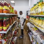 Yusupha Bojang grabs a jug of palm oil off of the shelf at his market on Wednesday, June 21, 2023 in Everett, Washington. (Olivia Vanni / The Herald)
