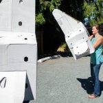 Averio Health Institute CEO Anna Martin, right, puts on a cardboard vertebrae. (Ryan Berry / The Herald)