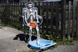 A plastic skeleton sits in a camping chair with its own plastic pool in the driveway of a home in Everett on Saturday, June 26, 2021. Temperatures reached 95 degrees on Saturday with a forecasted high of 103 degrees on Monday.  (Olivia Vanni / The Herald)