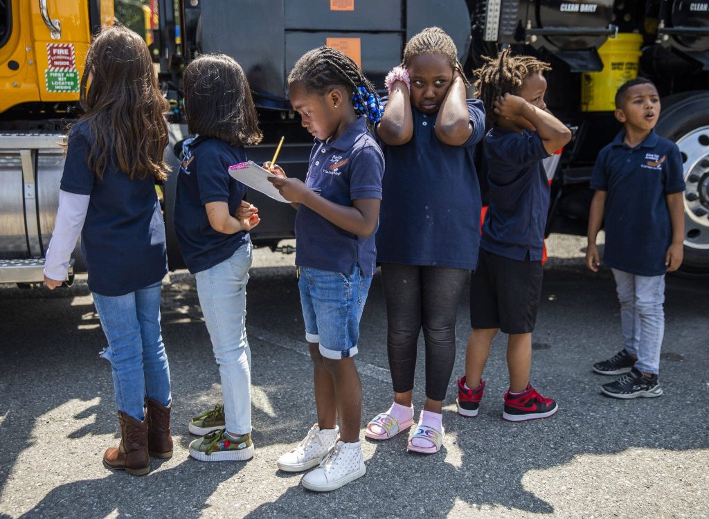 Binta Sanneh, 5, left, and Binta Sanneh, 6, right, line up along with other Rise Up Academy students to get a chance to climb into a truck on Thursday, July 6, 2023 in Everett, Washington. (Olivia Vanni / The Herald)