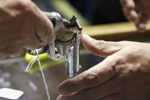 FILE - In this Oct. 20, 2017, file photo, a sales clerk hands a pistol, being sold on behalf of the Aberdeen Police Department, to a customer to look at before an auction at Johnny's Auction House, where the company handles gun sales for police departments and the Lewis County Sheriff's Office, in Rochester, Wash. After years of trying, the Washington state House of Representatives passed a bill Thursday, Jan. 23, 2020, that allows the State Patrol to destroy guns they confiscated during criminal investigations.  (AP Photo/Elaine Thompson, File)