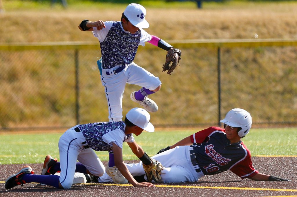 Everett All Star Ray Flores slides in safe at second between two Lake Stevens middle infielders during a 12u Little League matchup on Wednesday, July 5, 2023, at the Phil Johnson Ballfields in Everett, Washington. (Ryan Berry / The Herald)