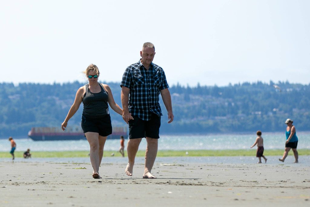 Shanon and Doug Davidson, of Duvall, walk hand in hand along the beach at Jetty Island. The couple brought their sons for a family day on the island. (Ryan Berry / The Herald)