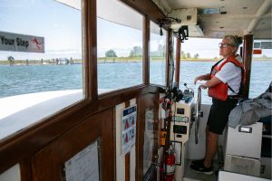 Capt. Kristi Schooley, of Argosy Cruises, navigates the Jetty Island ferry to the dock at while toting passengers to and fro on Friday, July 7, 2023, in Everett, Washington. (Ryan Berry / The Herald)