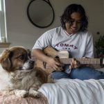 Thavoron plays his guitar at his apartment on Saturday, April 8, 2023 in Seattle, Washington. (Annie Barker / The Herald)