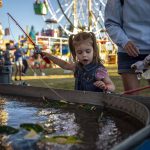 Emily Hillman, 2, left, secures a fish for a prize with their mom, Piper Hillman, 34, right, during the Kla Ha Ya Days carnival at Harvey Field in Snohomish, Washington on Thursday, July 13, 2023. (Annie Barker / The Herald)
