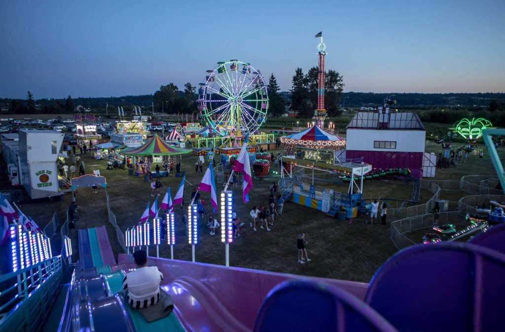 Rides shine as the sun sets during the Kla Ha Ya Days carnival at Harvey Field in Snohomish, Washington on Thursday, July 13, 2023. (Annie Barker / The Herald)