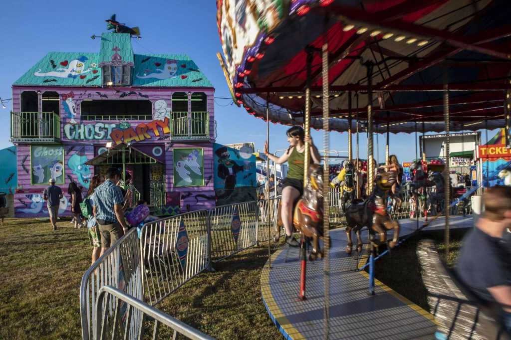 Individuals ride a carousel and wander the grounds during the Kla Ha Ya Days carnival at Harvey Field in Snohomish, Washington on Thursday, July 13, 2023. (Annie Barker / The Herald)