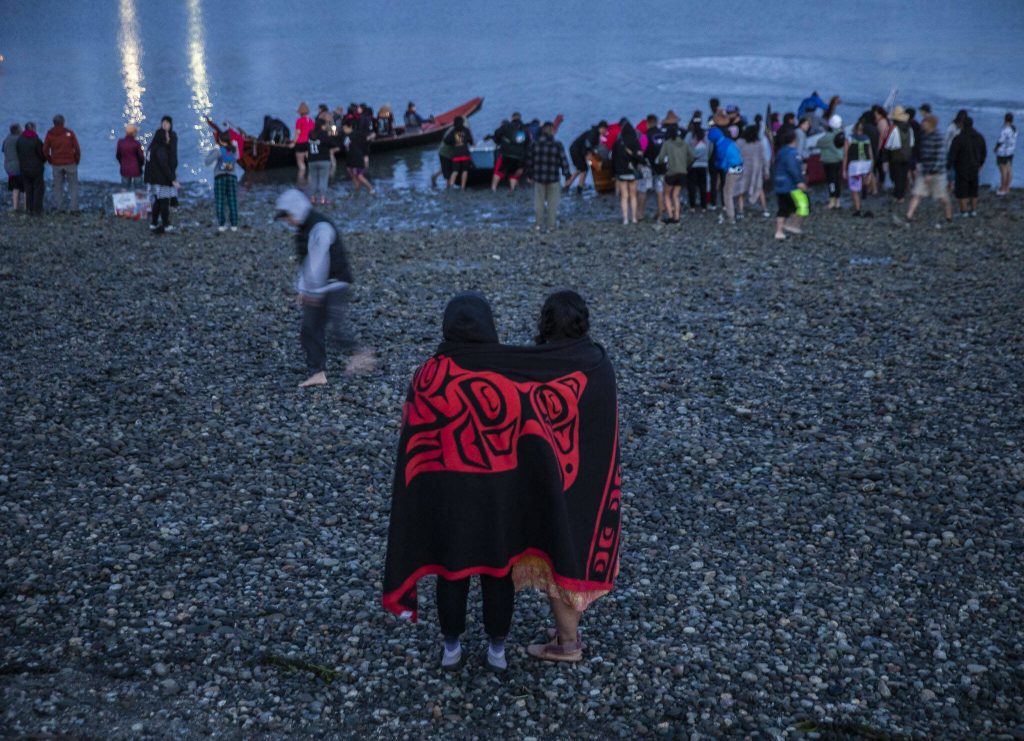 People watch from the shore as different Canoe Families set off from Tulalip for the next leg of the journey on Friday, July 28, 2023. (Olivia Vanni / The Herald)