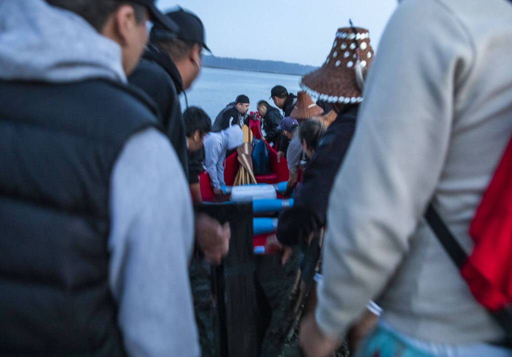 As the sun begins to the rise a Canoe Family maneuvers their canoe into the water on Friday, July 28, 2023 in Tulalip, Washington. (Olivia Vanni / The Herald)