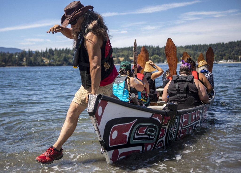 Skipper Jim Seller, 54, hops out of a canoe during the 2023 Washington Tribes Canoe Journey in Bellingham, Washington on Sunday, July 23, 2023. (Annie Barker / The Herald)