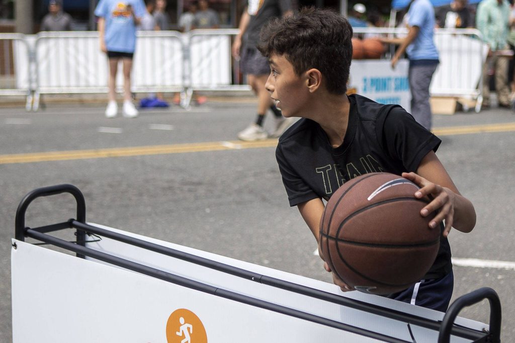 Jayden McGinness, 13, grabs a ball during the 3-point shot competition during the Everett 3on3 tournament Sunday in downtown Everett. (Annie Barker / The Herald)