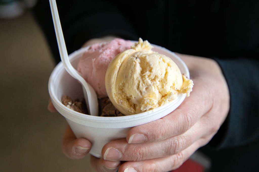 A customer holds a cup with three different flavors of ice cream at Kapaws Iskreme in Coupeville, Washington. Ryan Berry / The Herald photo