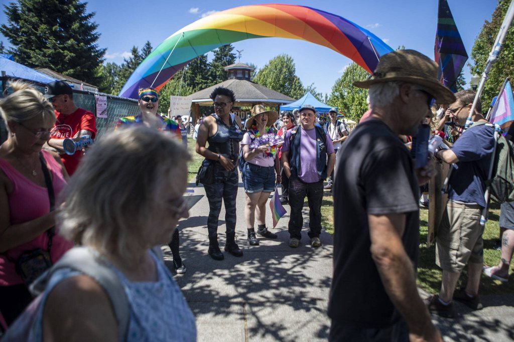 Attendees watch protesters pass by during the second annual Arlington Pride at Legion Memorial Park in Arlington, Washington on Saturday, July 22, 2023. (Annie Barker / The Herald)
