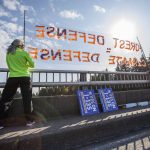 Kate Lunceford and Clara Clebe hold signs on the 7th Street I-5 overpass to protest for forest protection on Monday, June 26, 2023 in Everett, Washington. (Olivia Vanni / The Herald)