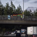 People hold a banner protesting for forest protection on the 112th Street I-5 overpass on Monday, June 26, 2023 in Everett, Washington. (Olivia Vanni / The Herald)