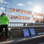 Kate Lunceford and Clara Clebe hold signs on the 7th Street I-5 overpass to protest for forest protection on Monday, June 26, 2023 in Everett, Washington. (Olivia Vanni / The Herald)