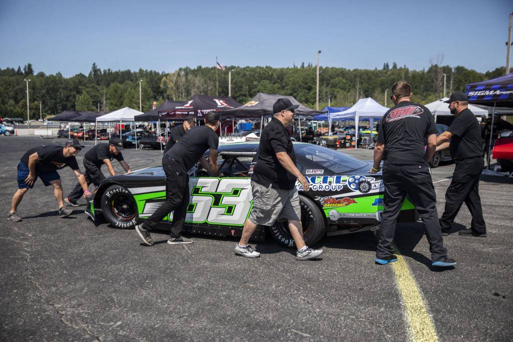 A tire is secured onto Preston Peltiers car during practice for Summer Showdown at Evergreen Speedway on Thursday in Monroe. (Olivia Vanni / The Herald)