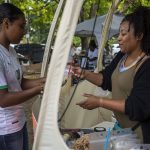 Tea Moss Shop Owner Takiyah Miller, right, serves a drink to a customer during the Nubian Jam at Forest Park in Everett, Washington on Saturday, July 29, 2023. (Annie Barker / The Herald)