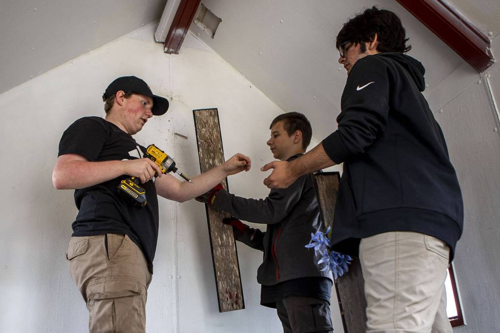 Left to right, Michael Durkee, 15, Braden Schoben, 13, and Haiden Sheffield, 15, remove a cross temporarily at the Wayside Chapel. Michael is leading the renovation effort for his Eagle Scout project. (Annie Barker / The Herald)