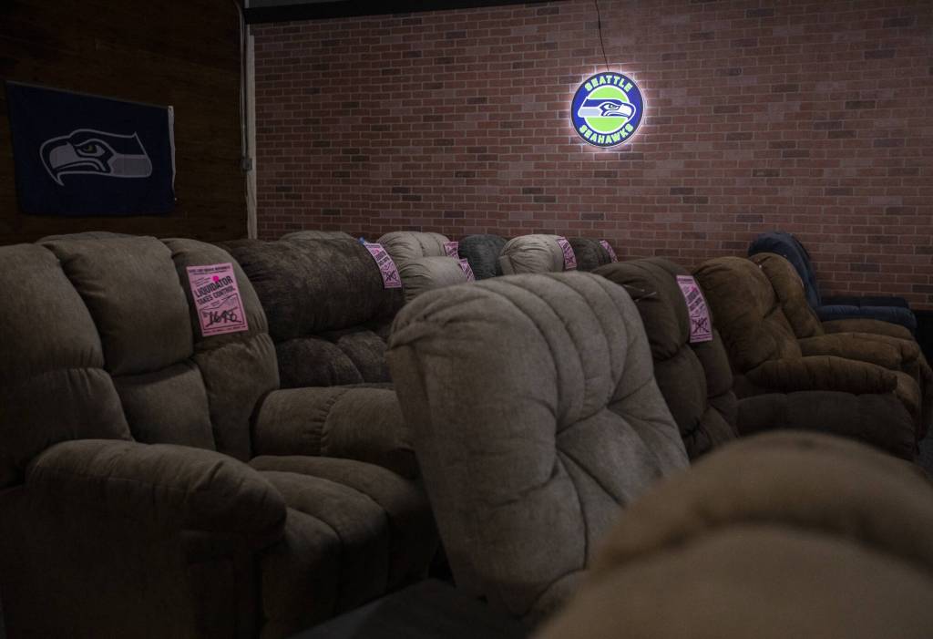 Furniture with liquidator price tags is illuminated by a Seahawks sign on Thursday, Aug. 24, 2023 in Everett, Washington. (Olivia Vanni / The Herald)
