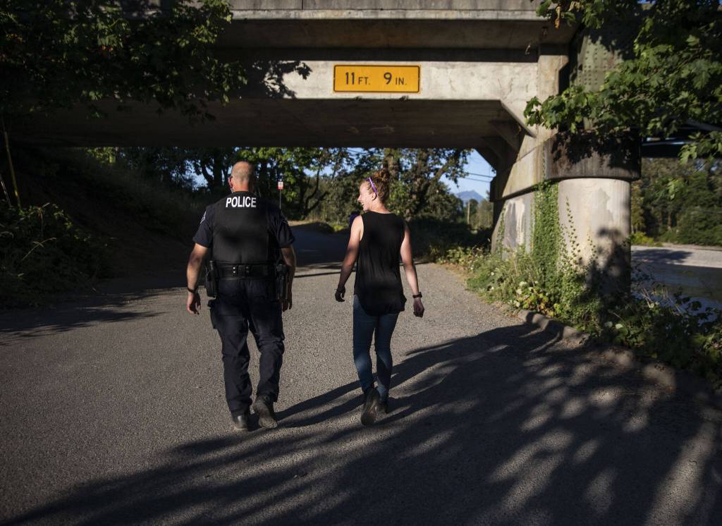 Jessi Beyer, right, and Monroe police officer Van Eaton walk along the river at Lewis Street Park on Wednesday, Aug. 2, 2023, in Monroe, Washington. (Olivia Vanni / The Herald)