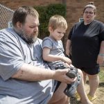 Marc Boucher helps Maverick Boucher, 4, put on his shoes as Amanda Boucher stands by to assist at the Interfaith Family Shelter in Everett on Sunday. (Annie Barker / The Herald)