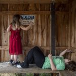 Mia Boucher, 9, playfully adds a sticker over the 2 in a notice that allows only 21-year-olds in the smoking area while her sister Makayla Boucher, 11, plays on a phone. (Annie Barker / The Herald)