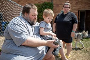 Marc Boucher, left, helps Maverick Boucher, 4, put on his shoes as Amanda Boucher, right, stands by to assist at the Interfaith Association of Northwest Washington located at 2520 Cedar Street in Everett, Washington on Sunday, July 30, 2023. (Annie Barker / The Herald)