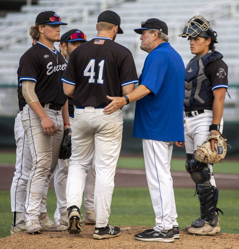 Everett Merchants manager Harold Pyatte gathers players on the mound during a game on Friday at Funko Field in Everett. (Annie Barker / The Herald)