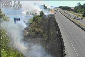 Traffic cameras on Tuesday showed heavy smoke and flames at separate fires in dry grass right along the freeway, near the exits to 144th and 156th streets NE. (Washington State Department of Transportation)