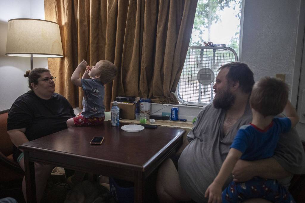 Left to right, Amanda Boucher, Carter Boucher, 2, Marc Boucher, and Maverick, 4, sit together at a motel in Arlington, Washington on Thursday, Aug. 10, 2023. (Annie Barker / The Herald)