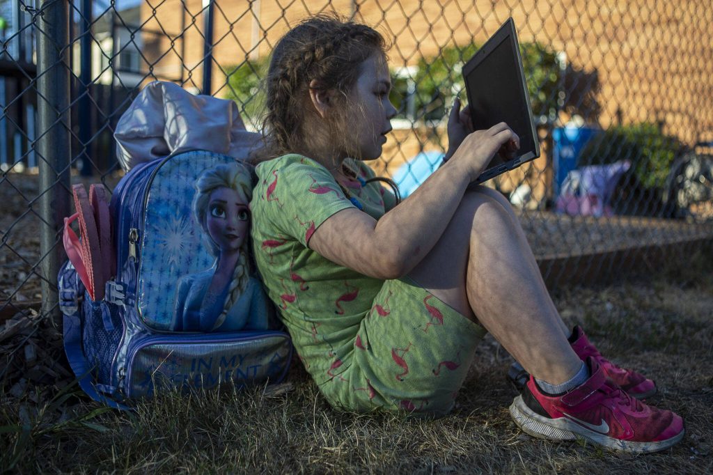 Mia Boucher, 9, plays on a computer borrowed from a school as they wait to move out at the Interfaith Association of Northwest Washington in Everett, Washington, on Wednesday, Aug. 2, 2023. (Annie Barker / The Herald)