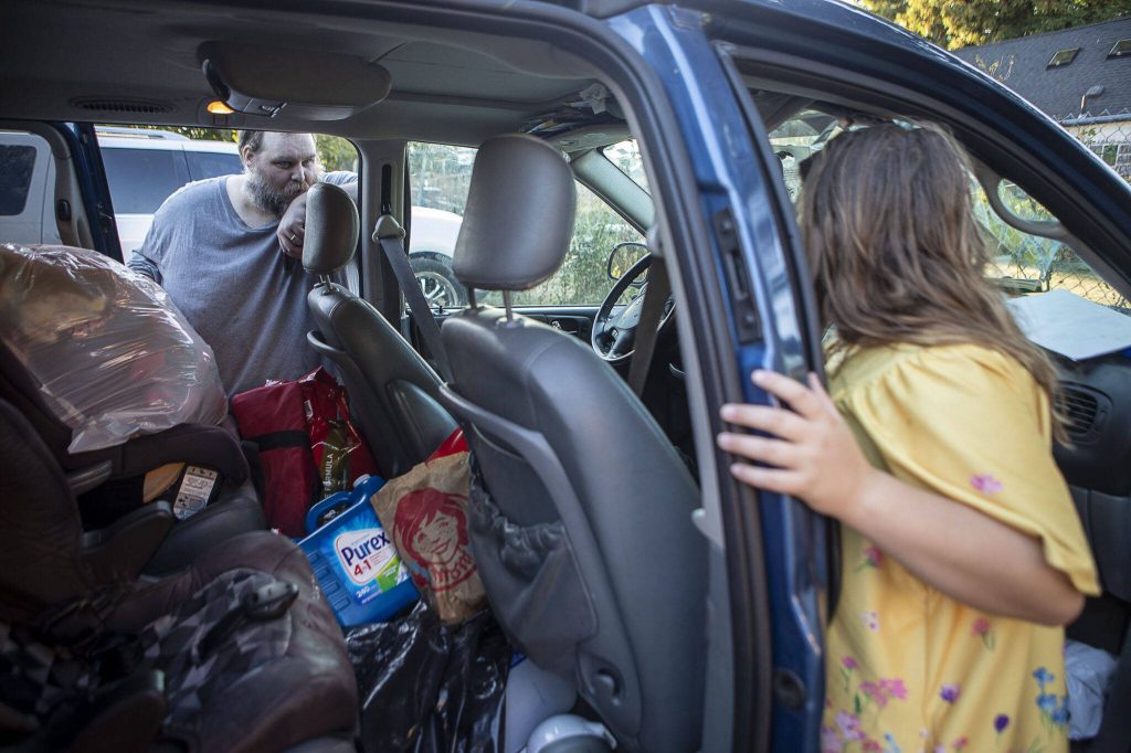 Marc Boucher, left, looks into the family van with Makayla Boucher, 11, as they prepare to leave the Interfaith Association of Northwest Washington in Everett, Washington, on Wednesday, Aug. 2, 2023. (Annie Barker / The Herald)