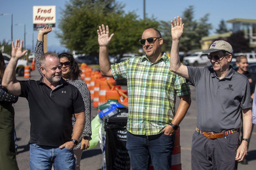 People involved with the project raise their hands during a ribbon cutting ceremony to celebrate the completion of the 196th Street SW Improvement Project near the 196th and 44th Ave West intersection in Lynnwood, Washington on Tuesday, Aug. 15, 2023. (Annie Barker / The Herald)